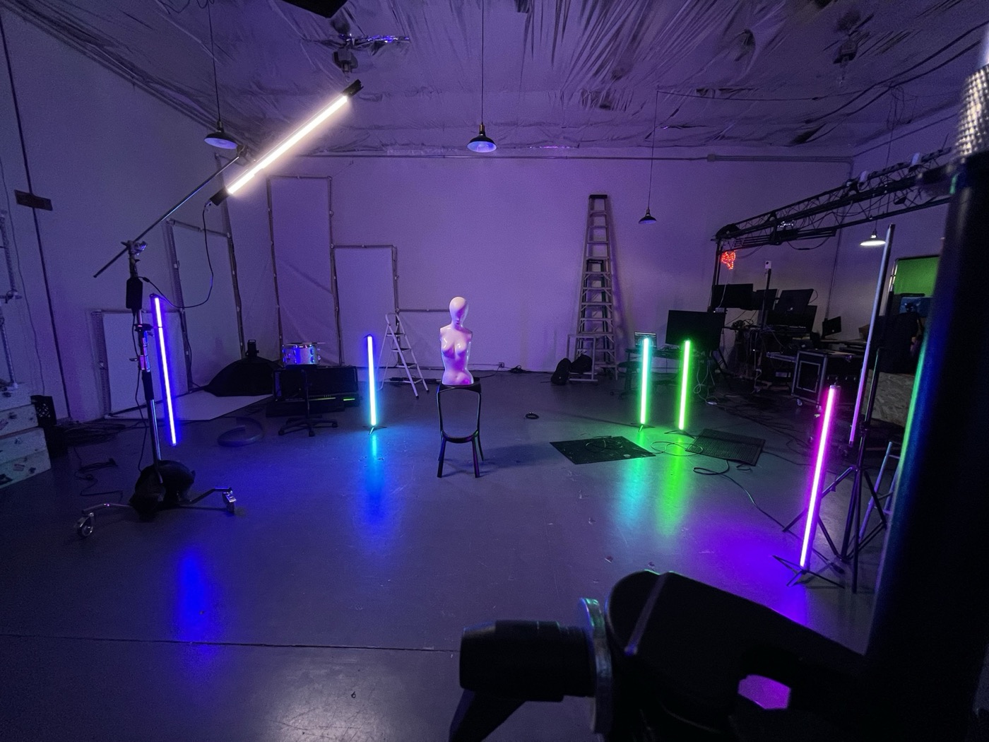 A studio space with rows of standing light tubes around an open floor area used for filming and recording performances.